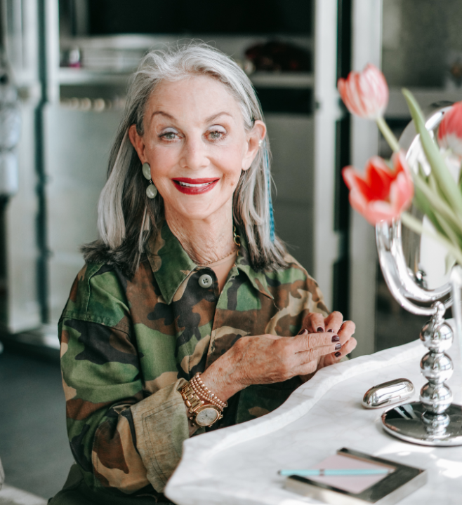 Honey Good sitting at her vanity, smiling with her signature red lipstick her best makeup over 50