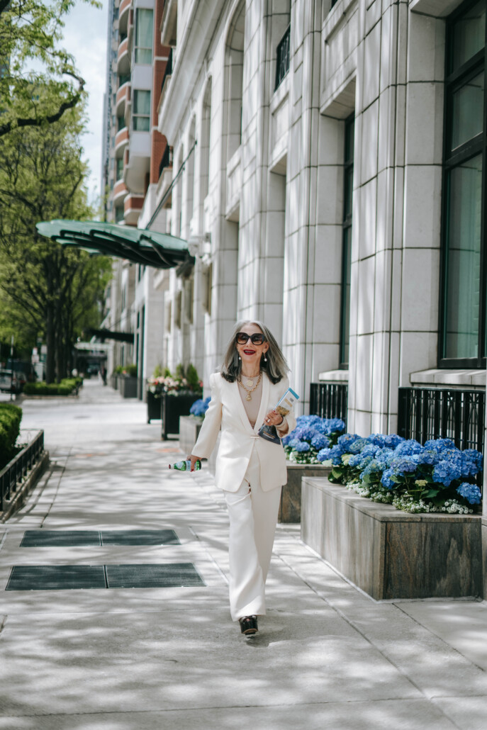 Image of honey good walking down a Chicago street wearing a white power suit looking full of resilience and authenticity