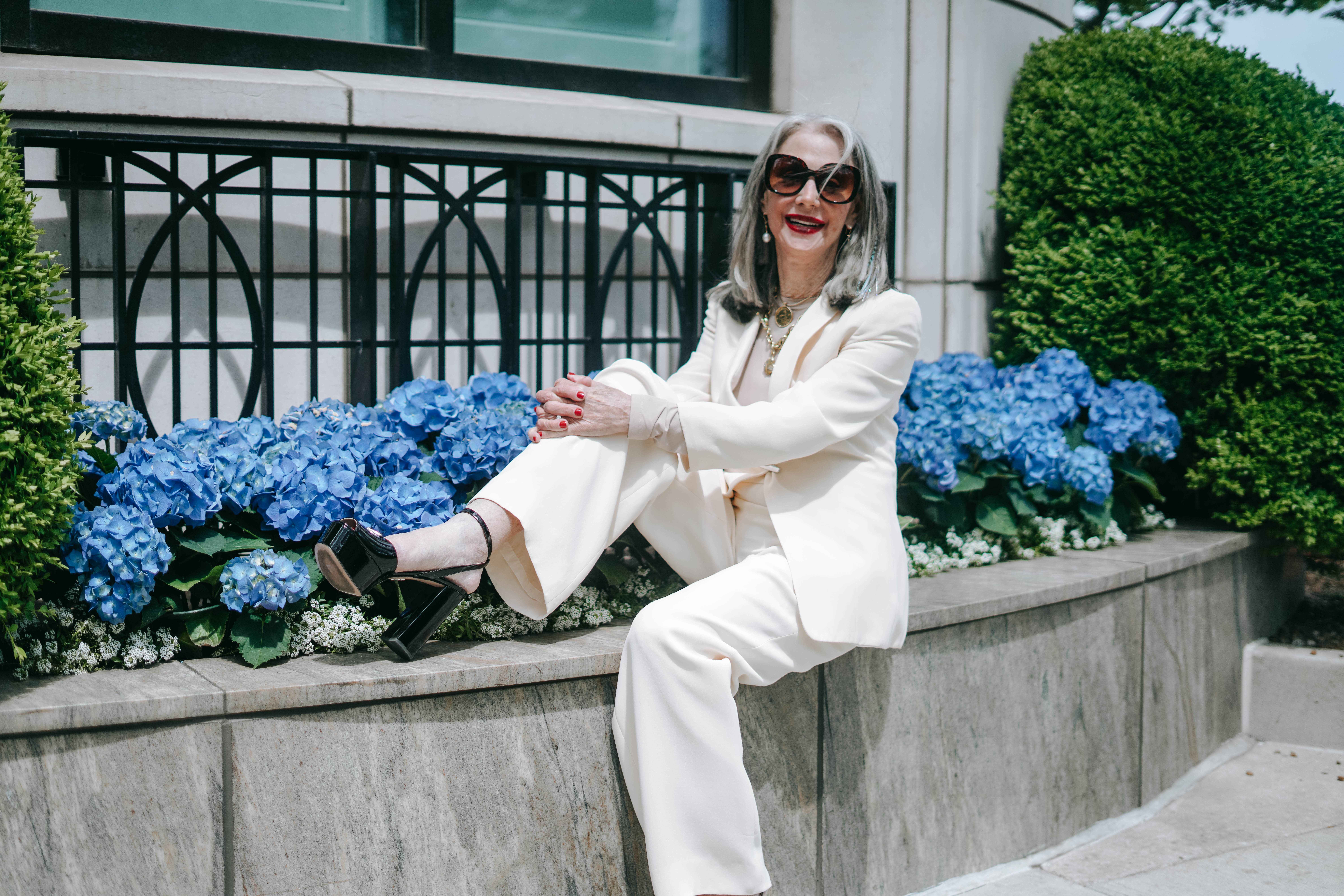 Image of honey good sitting on a concrete raised flower bed outside of a building in Chicago, filled with blue hydrangeas